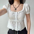Selfie shot of a woman in a white lace-trimmed puff sleeve top, arms slightly outstretched
