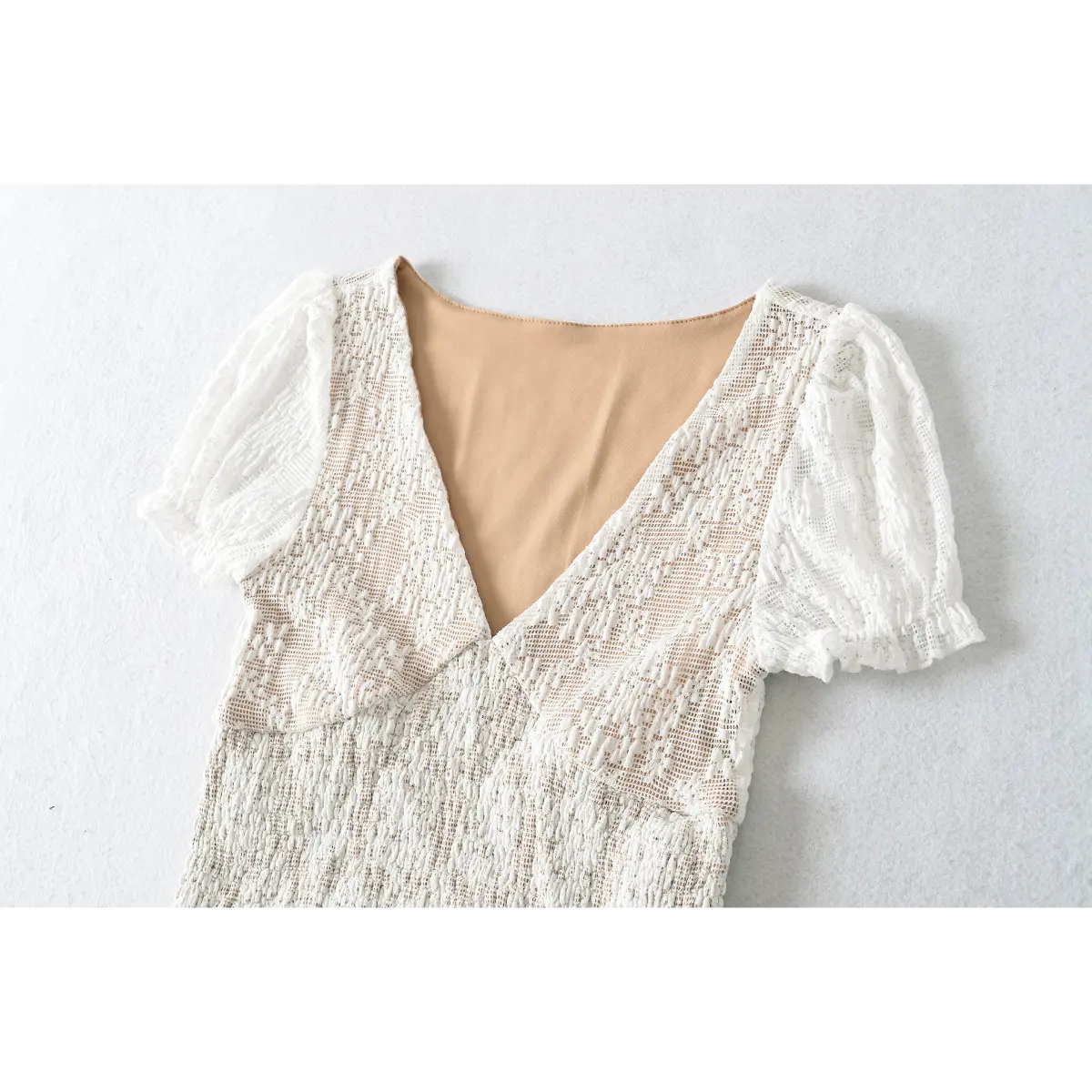 White lace short-sleeve top laid flat, showing back silhouette and scalloped hem