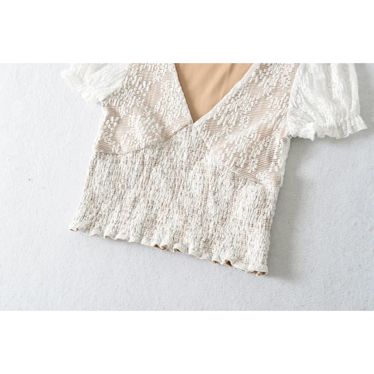 White lace short-sleeve top laid flat, showing front silhouette and lace pattern