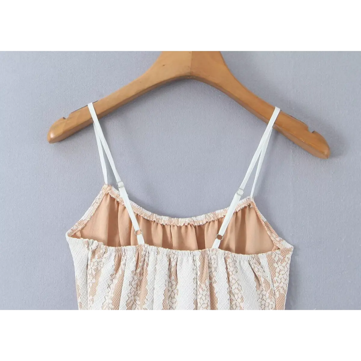 Close-up back view of a white lace spaghetti-strap dress, showing the adjustable straps, nude lining, and gathered bodice.
