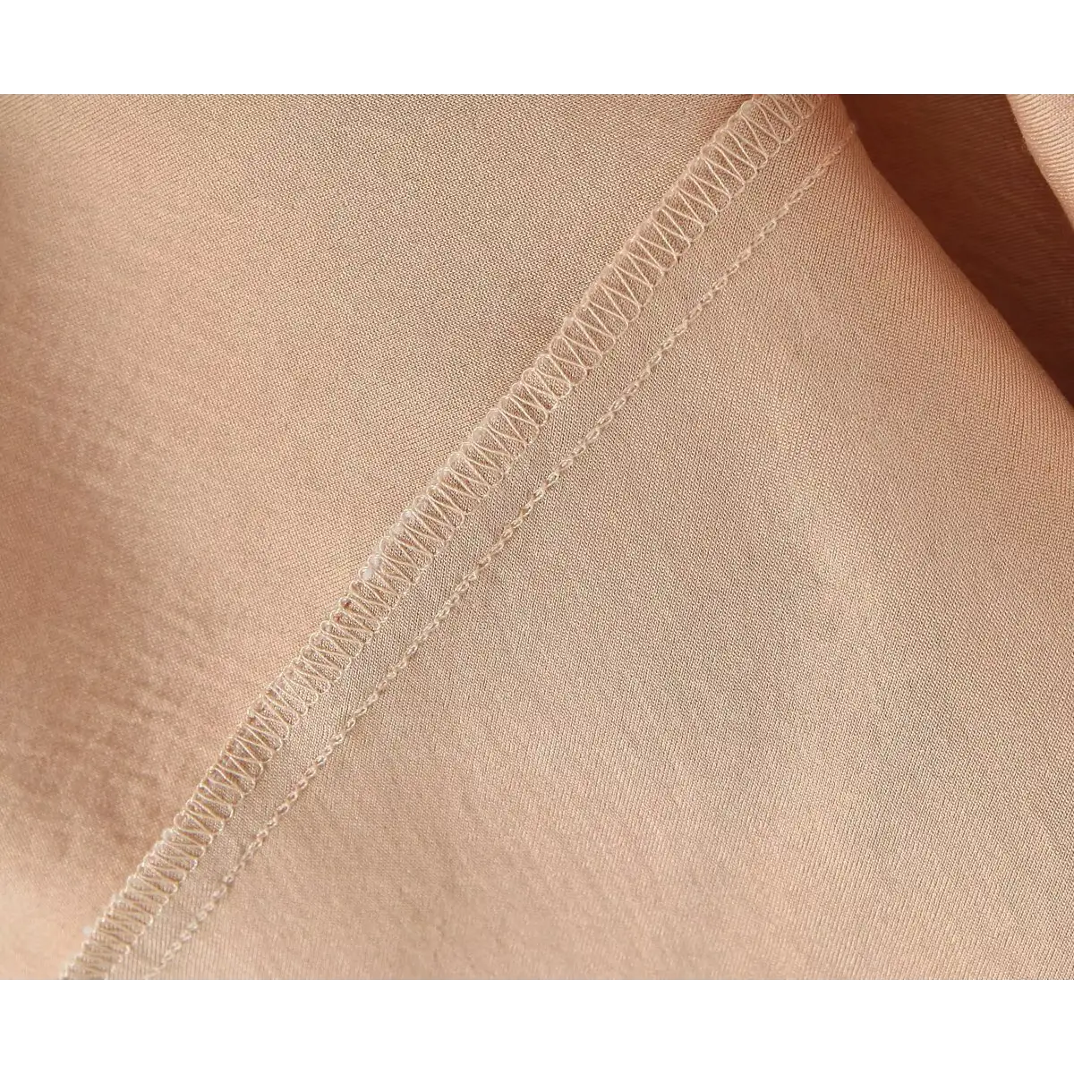 Close-up shot of the nude lining and stitching on a white lace spaghetti-strap dress, showing the elasticated seam finish.