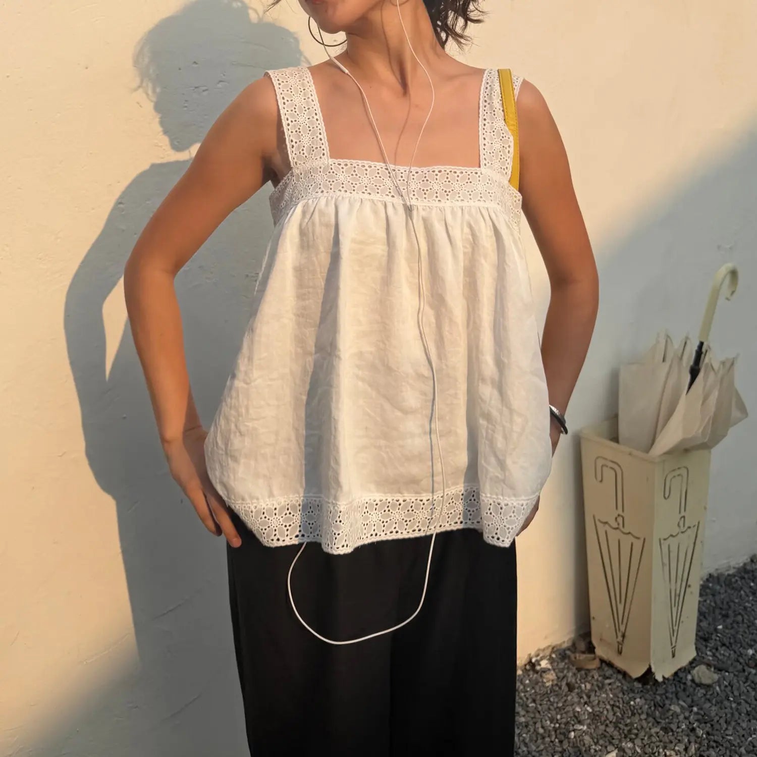 Female model in white eyelet lace square strap cami top, hands on hips outdoor shot, loose casual summer sleeveless top