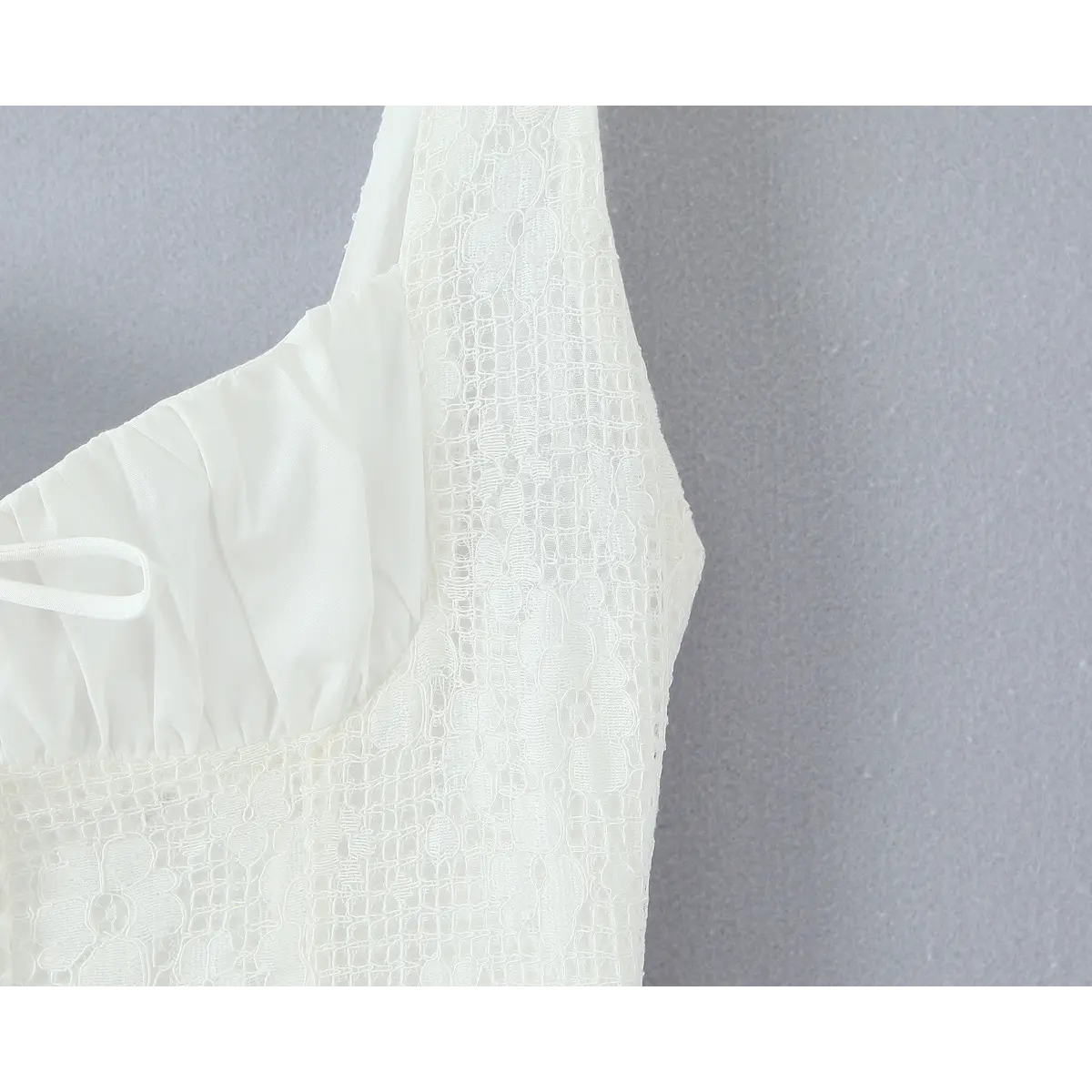 Close-up of the ruched bust panel and center front bow detail on the white lace dress