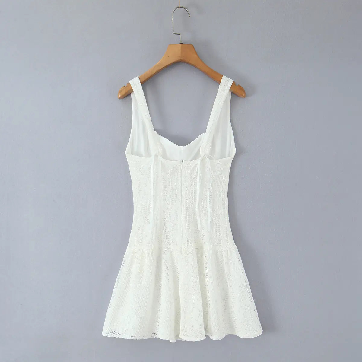 Full back view of the white lace mini dress on a wooden hanger, showing back ties and zipper closure
