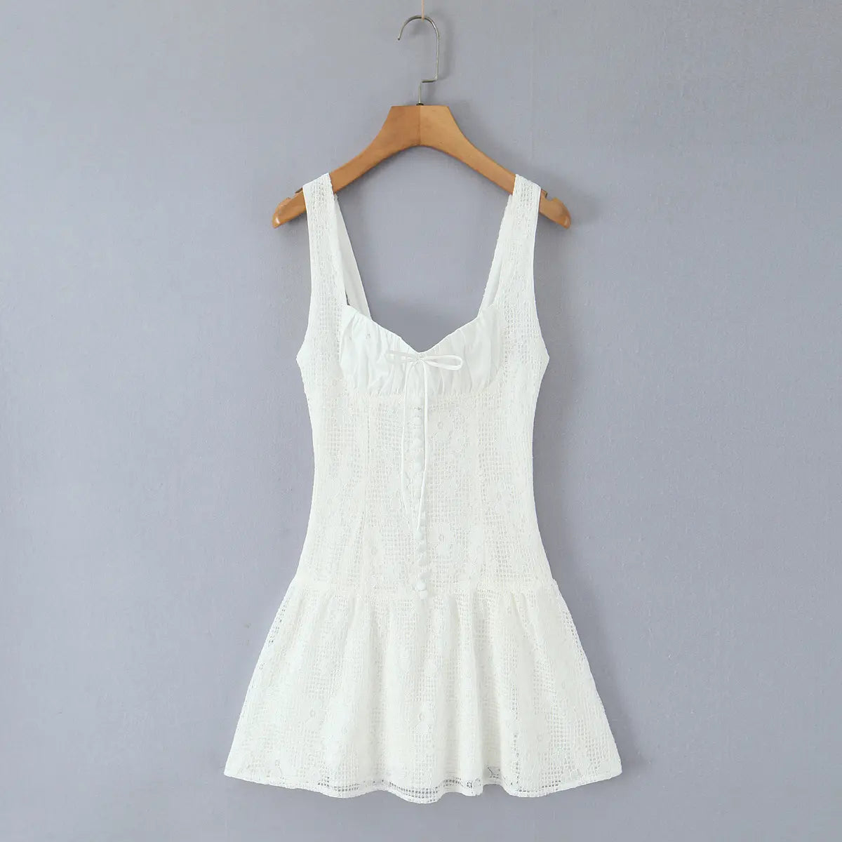 Full front view on wooden hanger of the white lace mini dress, showing full silhouette and center buttons