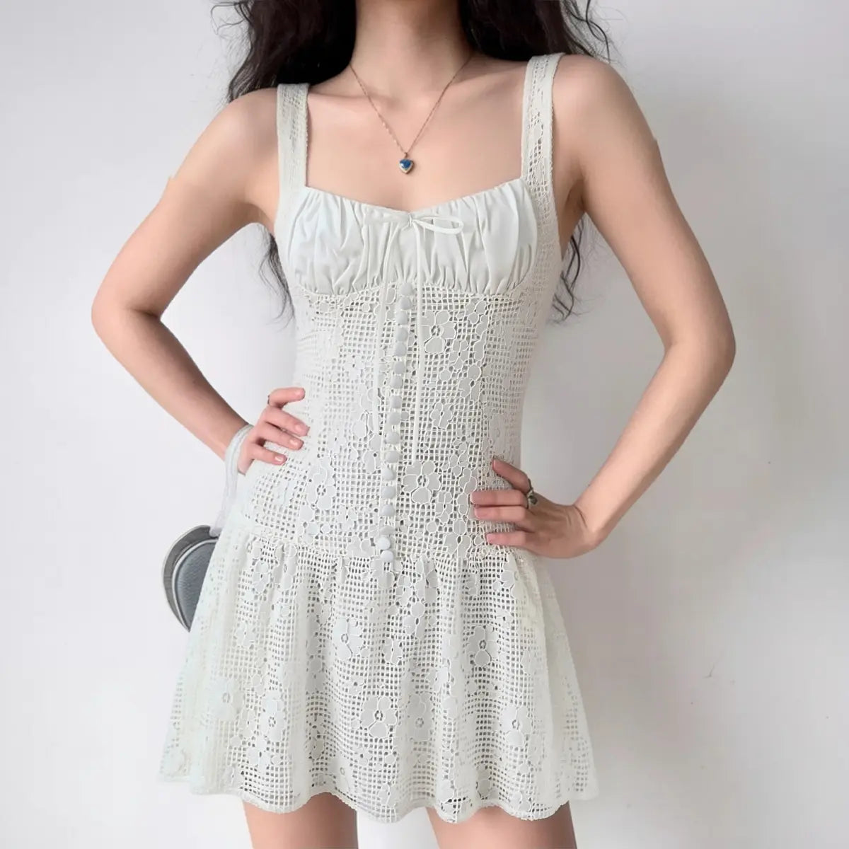 Lifestyle shot of model wearing the white floral lace square-neck mini dress, showing full silhouette, ruched bust panel, center buttons and flared skirt