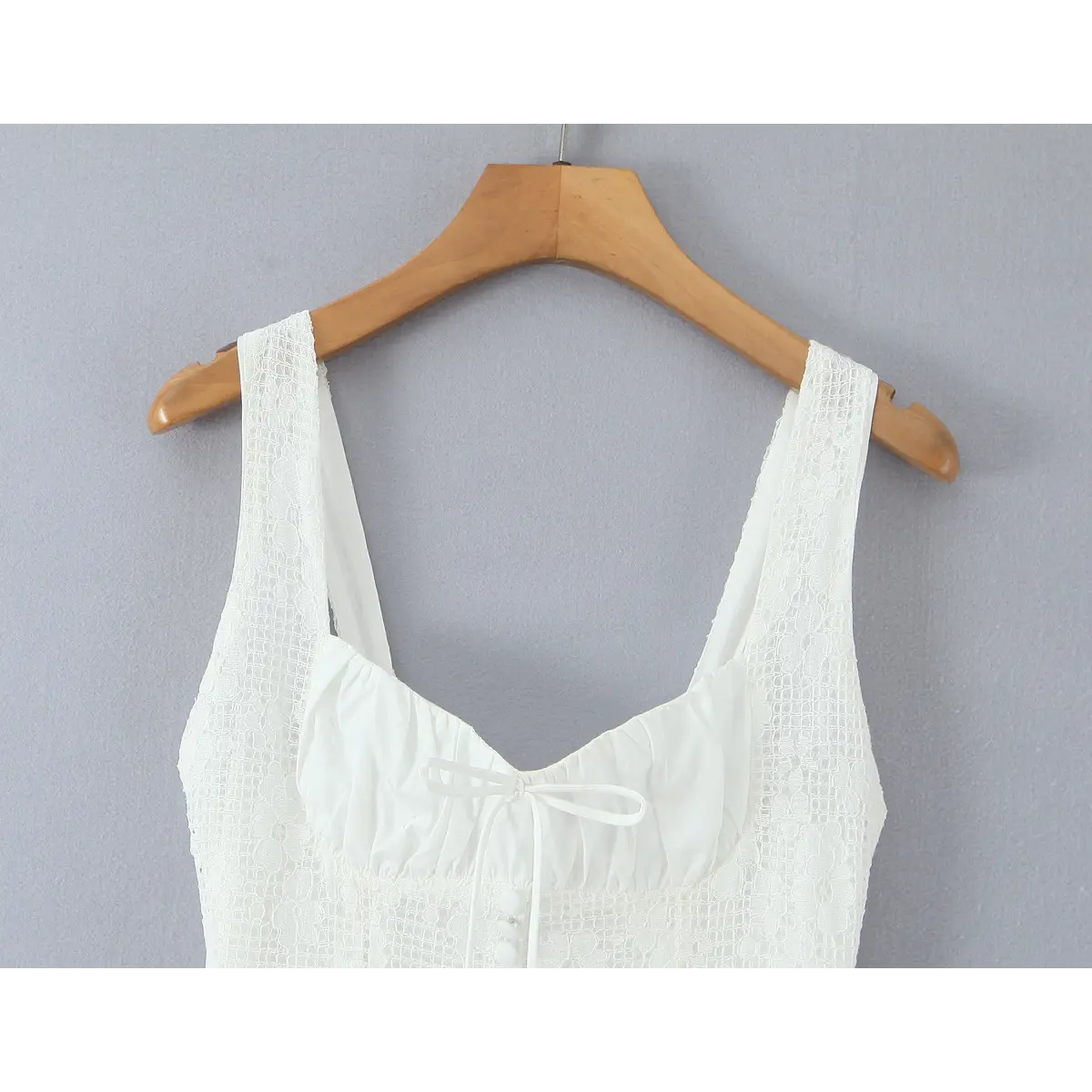 Partial view on wooden hanger showing the wide lace straps and sweetheart neckline of the dress