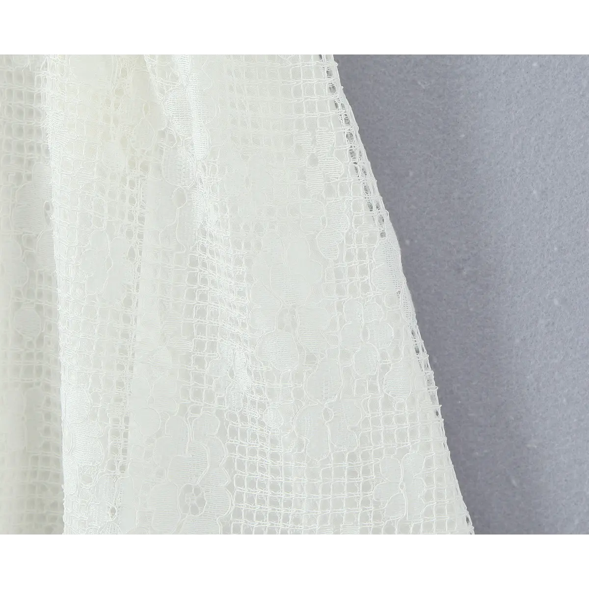 Close-up of the intricate floral lace hem on the flared skirt of the white dress