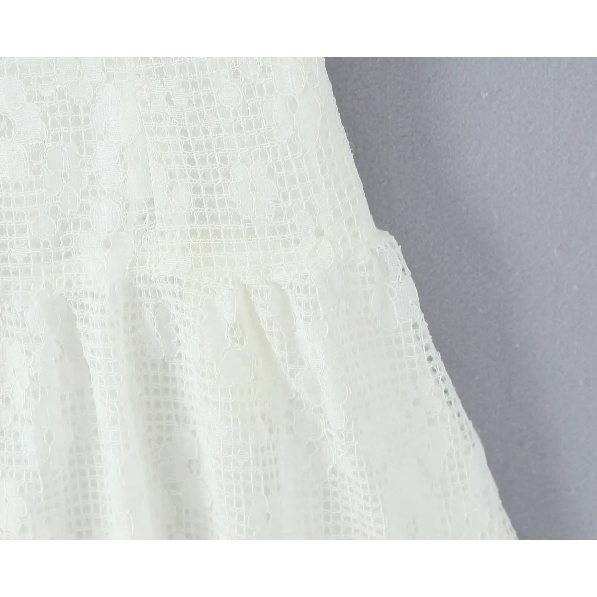 Close-up of the flared skirt seam on the white lace dress, showing floral lace pattern