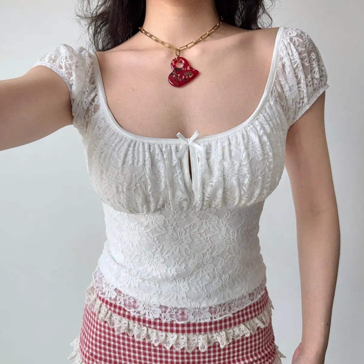 Front view of the same top, highlighting the gathered bust, center bow detail, and floral lace pattern.