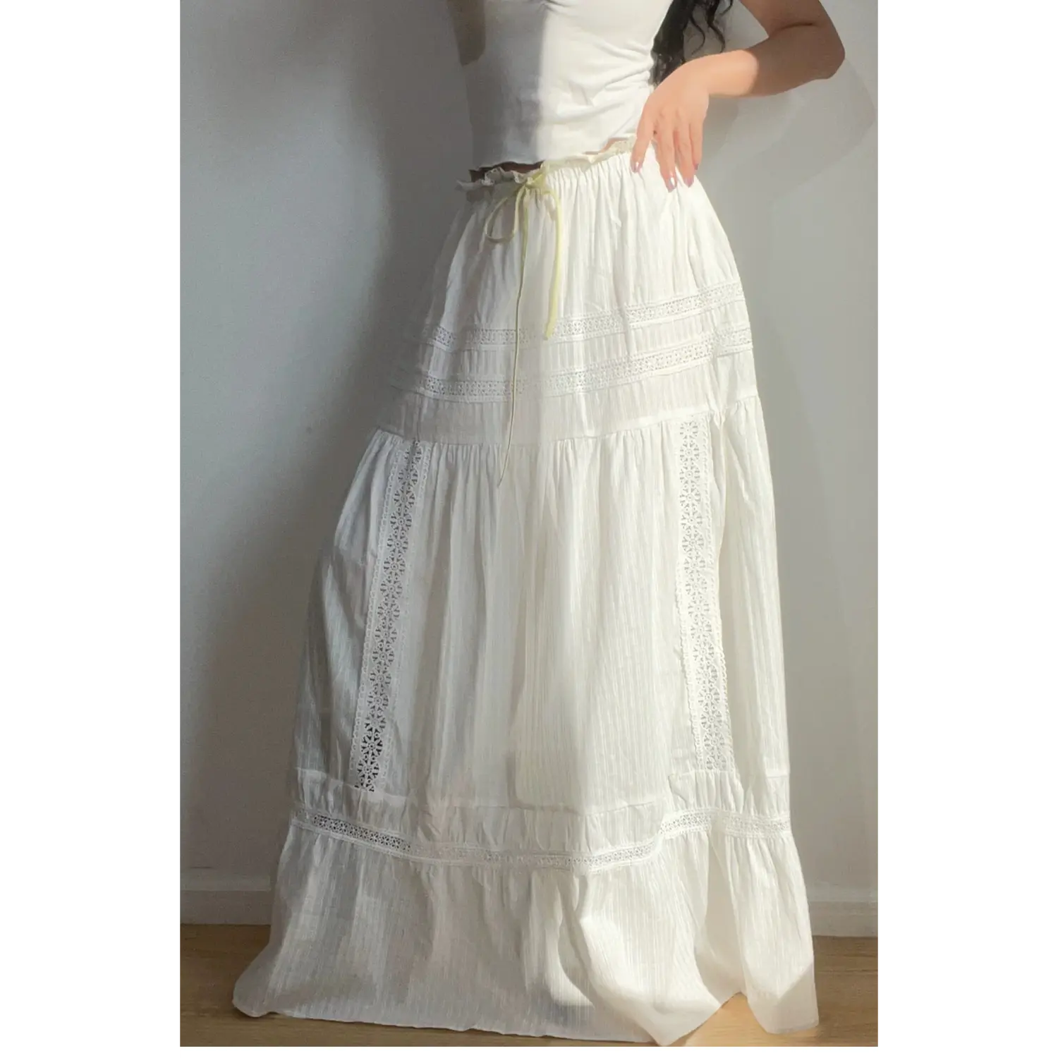 Close-up shot of the white lace tiered maxi skirt, highlighting the waist ruffle, yellow drawstring, and intricate lace details.