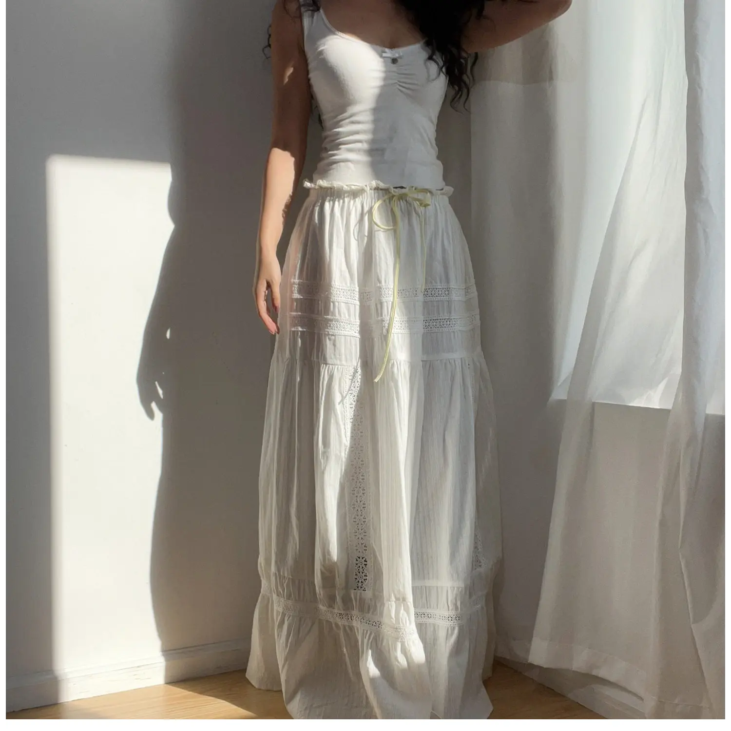 Profile shot of the woman in the white lace tiered maxi skirt, showing the side lace panels and flowy silhouette.