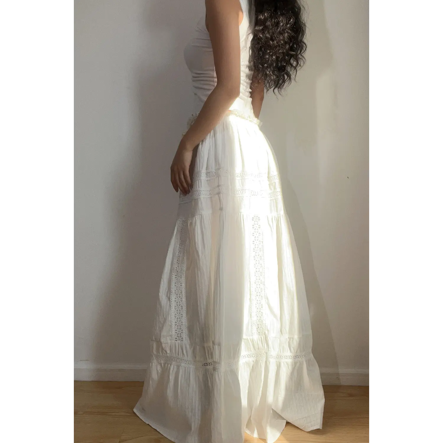Close-up of the waistband on the white lace tiered maxi skirt, featuring a ruffled edge and yellow drawstring tie.