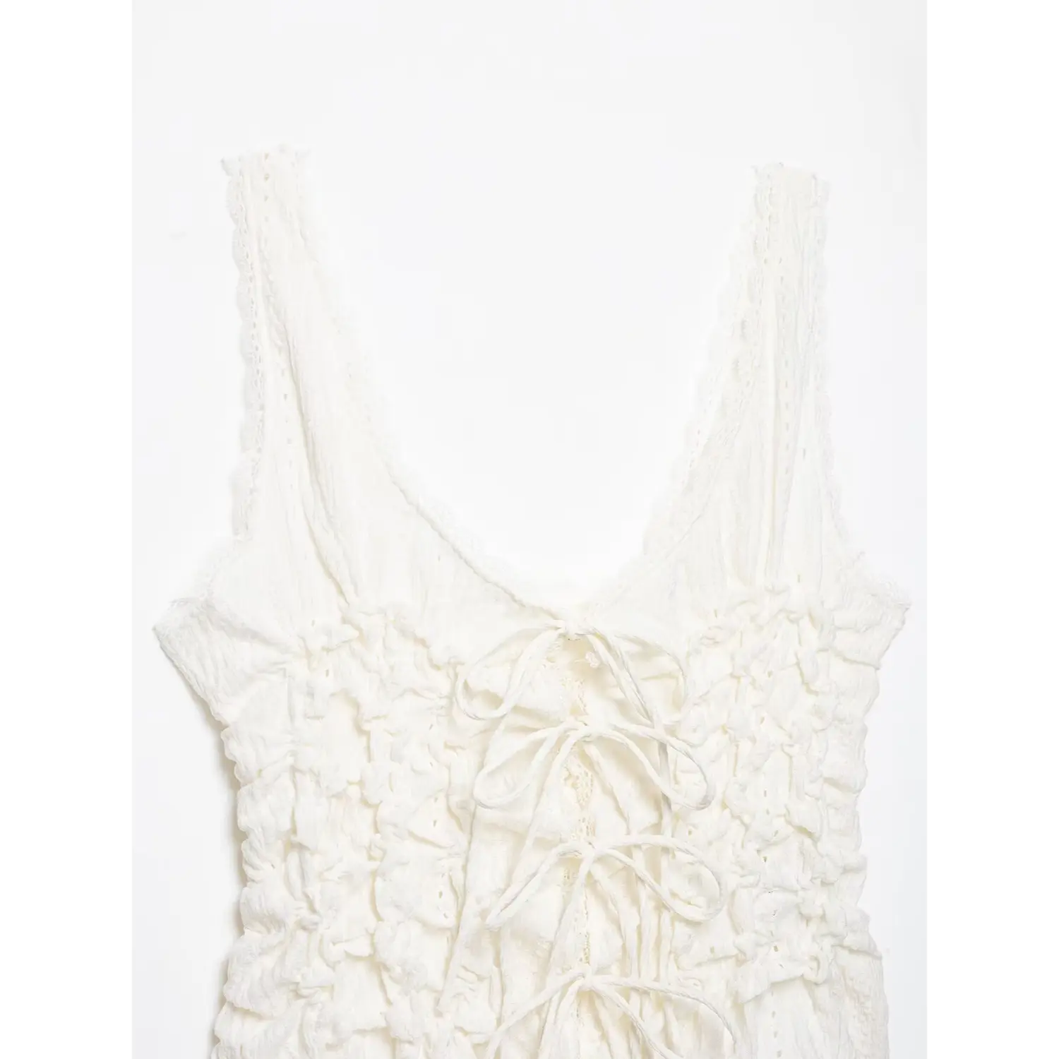 Close‑up shoulder view of white cami top, scalloped lace trim straps, v‑neckline, ruched textured fabric, white background