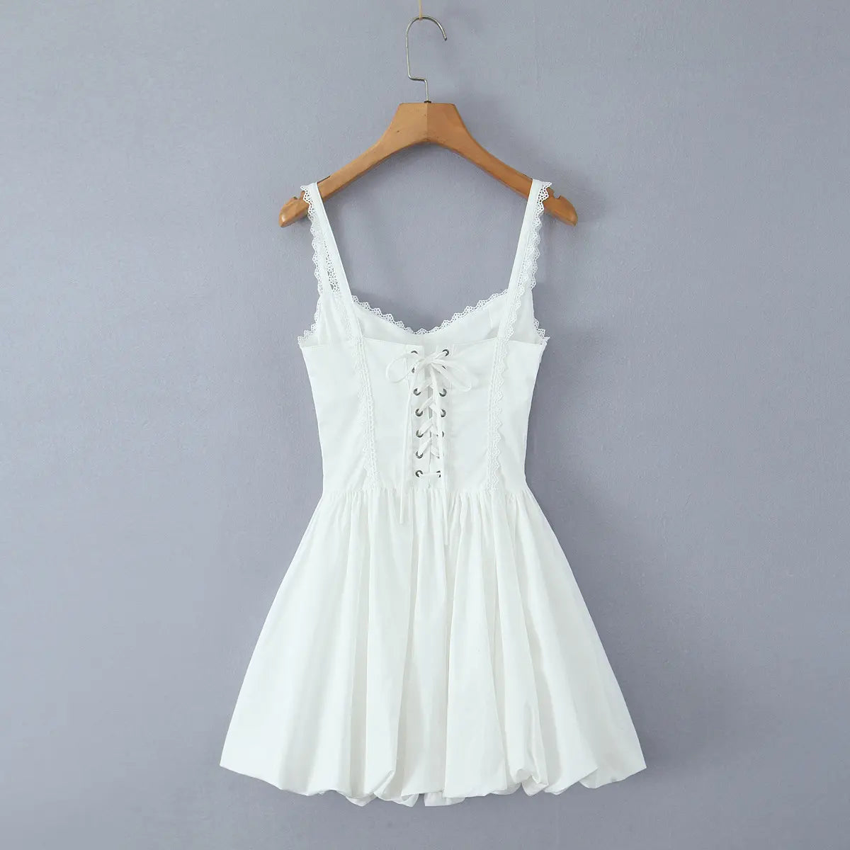 Full back view on wooden hanger of the white dress, showing corset-style lace-up closure