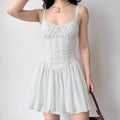 Lifestyle shot of model wearing white lace-trim corset-style puffball mini dress, showing full silhouette with lace straps, bow detail, and voluminous skirt