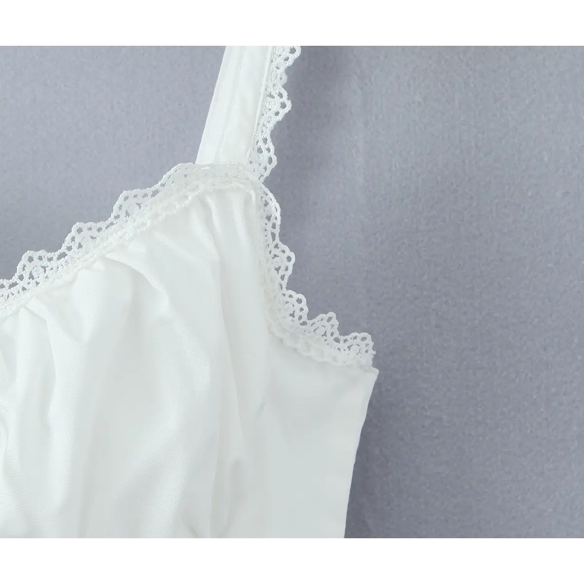 Close-up of the scalloped lace trim on the square neckline of the white dress
