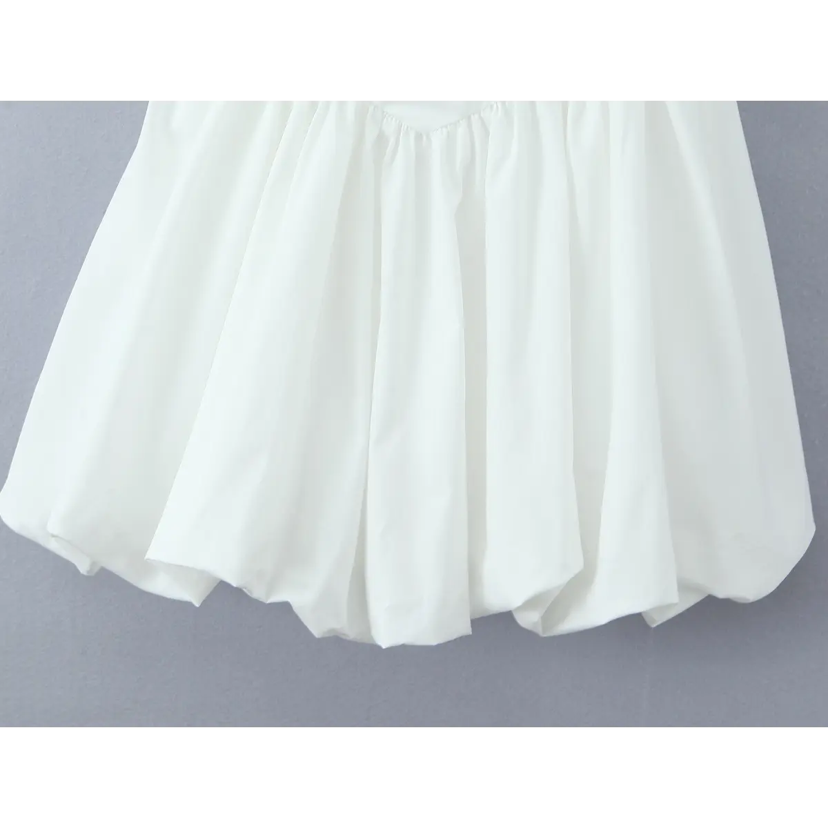 Close-up of the voluminous puffball skirt hem on the white lace-trim corset dress