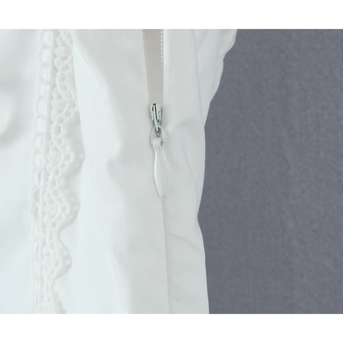 Close-up of the hidden side zipper with a fabric pull tab on the white dress