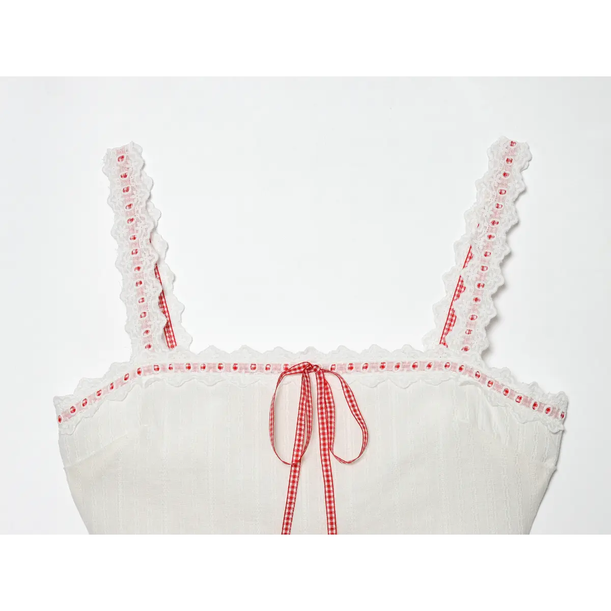 Full front view of a white lace-trimmed camisole with red accents, featuring a red gingham ribbon bow, lace straps, and a ruffled hem, isolated on a white background.