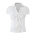 Studio shot of a white bustier-style shirt with a pointed collar, puff sleeves, lace trim, and two front tie closures.