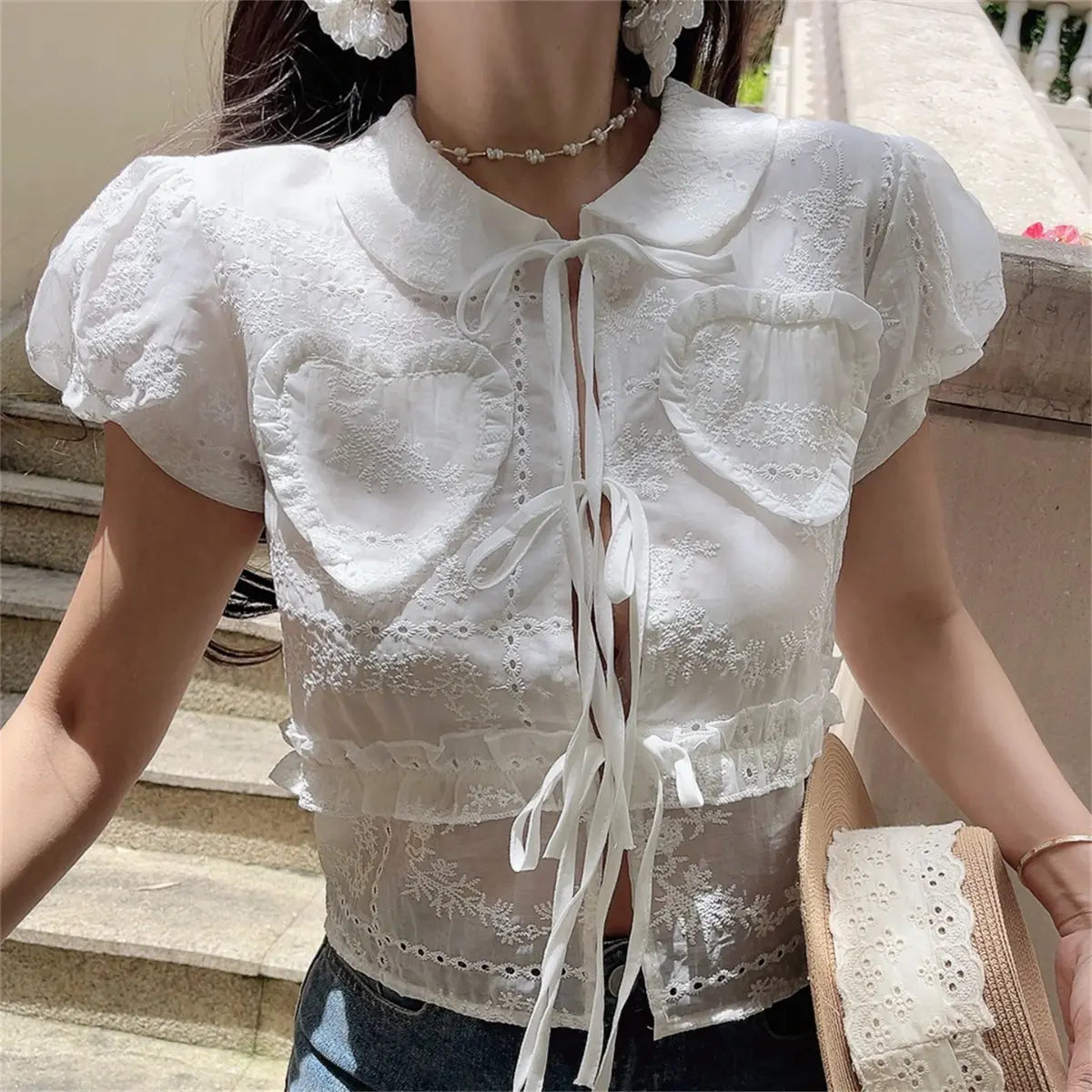 The white embroidered blouse styled with a straw hat, highlighting the Peter Pan collar.