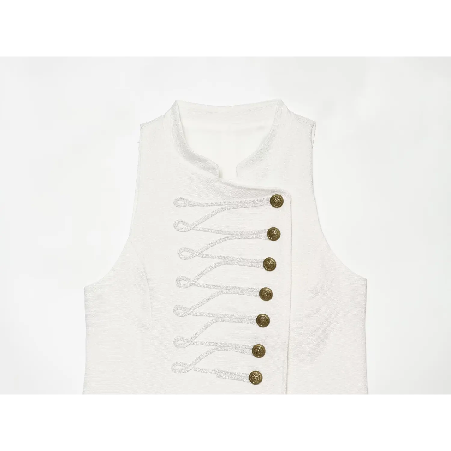 Close‑up of dress bodice, decorative braided cord and vintage gold metal buttons on white sleeveless mini dress