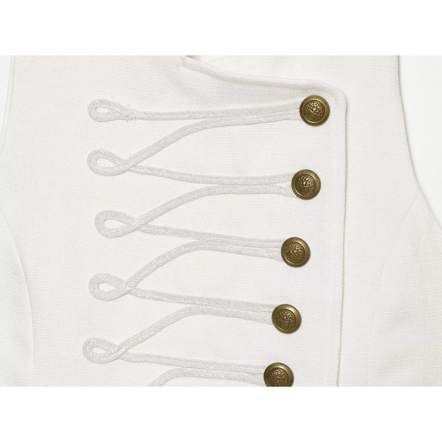 Macro shot of decorative braided cord embroidery and embossed vintage gold buttons on white dress