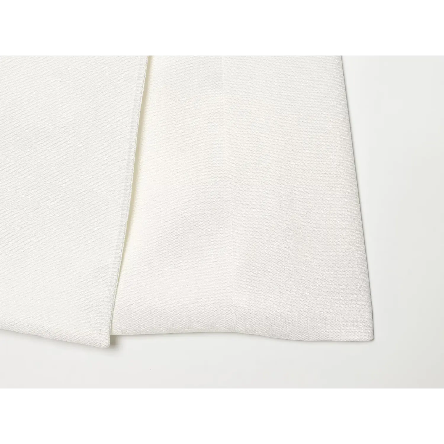 Close‑up hem view of white sleeveless military mini dress, woven fabric texture and clean finished hem