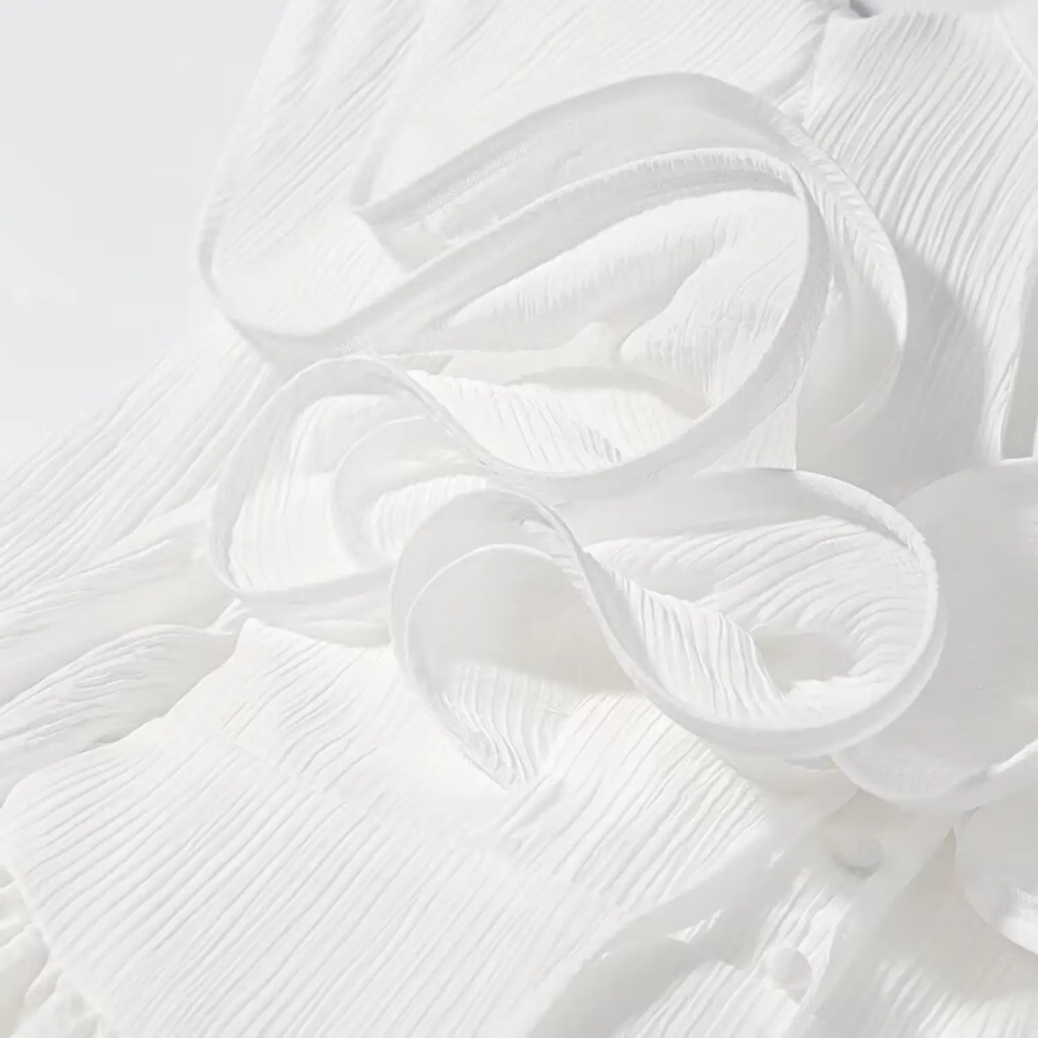 Macro closeup of three-dimensional spiral flower ornament on white wrinkled fabric dress