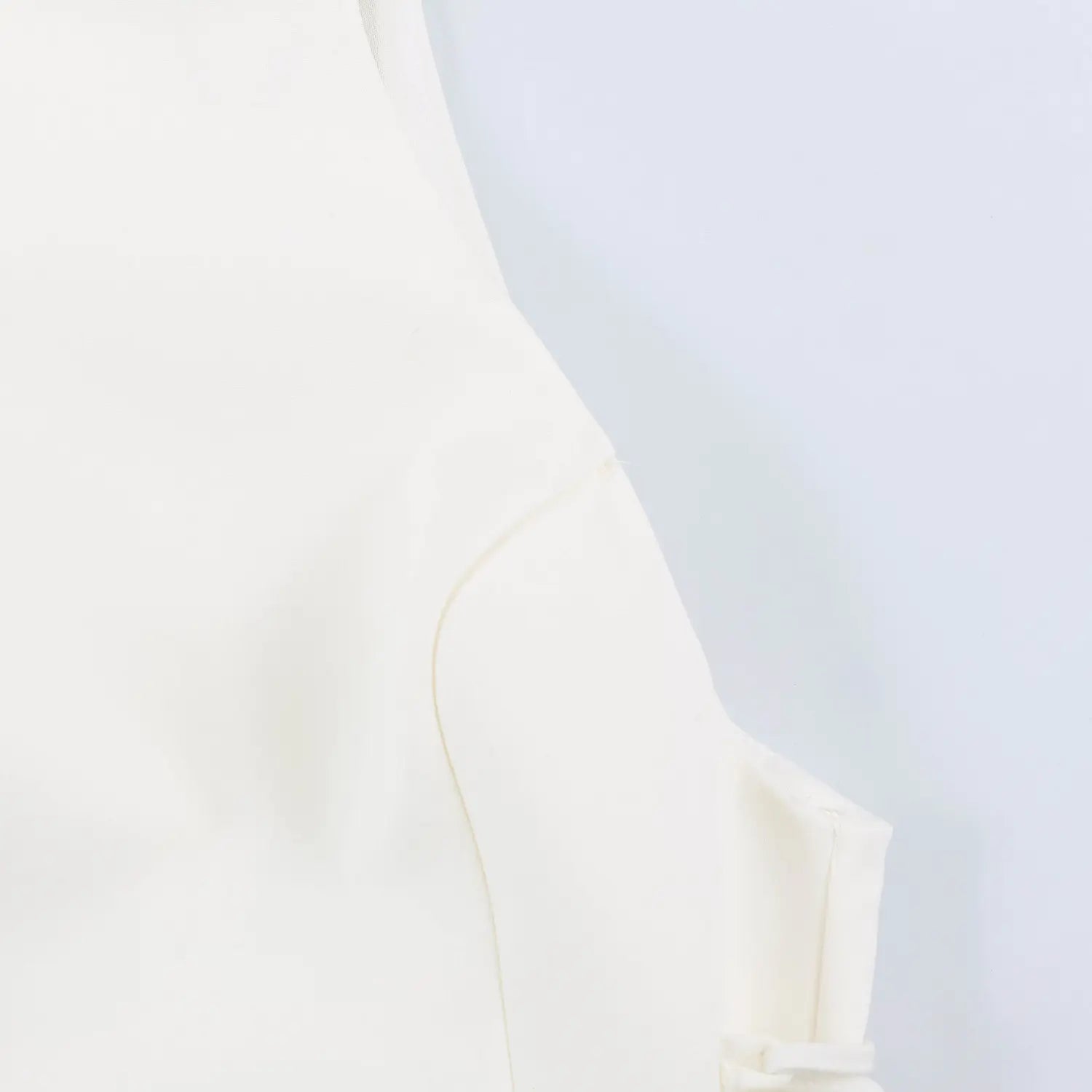 Close-up stitching detail of structured bodice on white halter mini dress