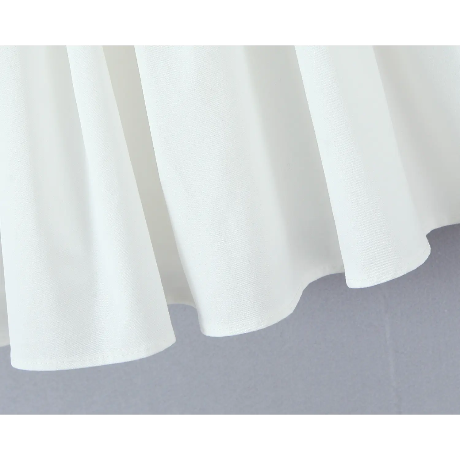 Closeup skirt hem, neatly finished stitched edge of white flared mini dress skirt