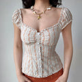 Front lifestyle shot on model of white floral stripe blouse, square neck, front faux buttons, ruffle trim, short puff sleeves