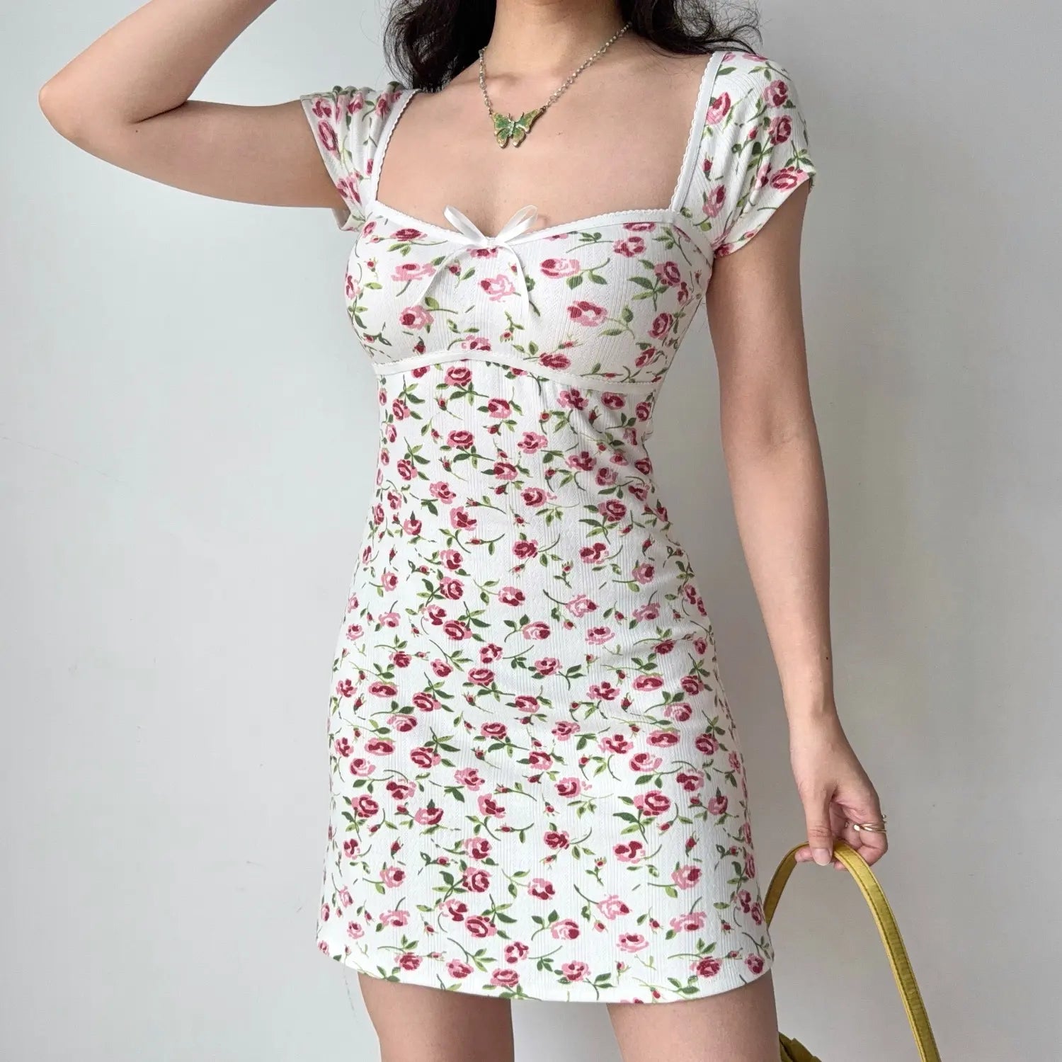 Front lifestyle shot on model of floral ribbed mini dress, square neckline, front tiny bow decor, cap sleeves, slim short dress