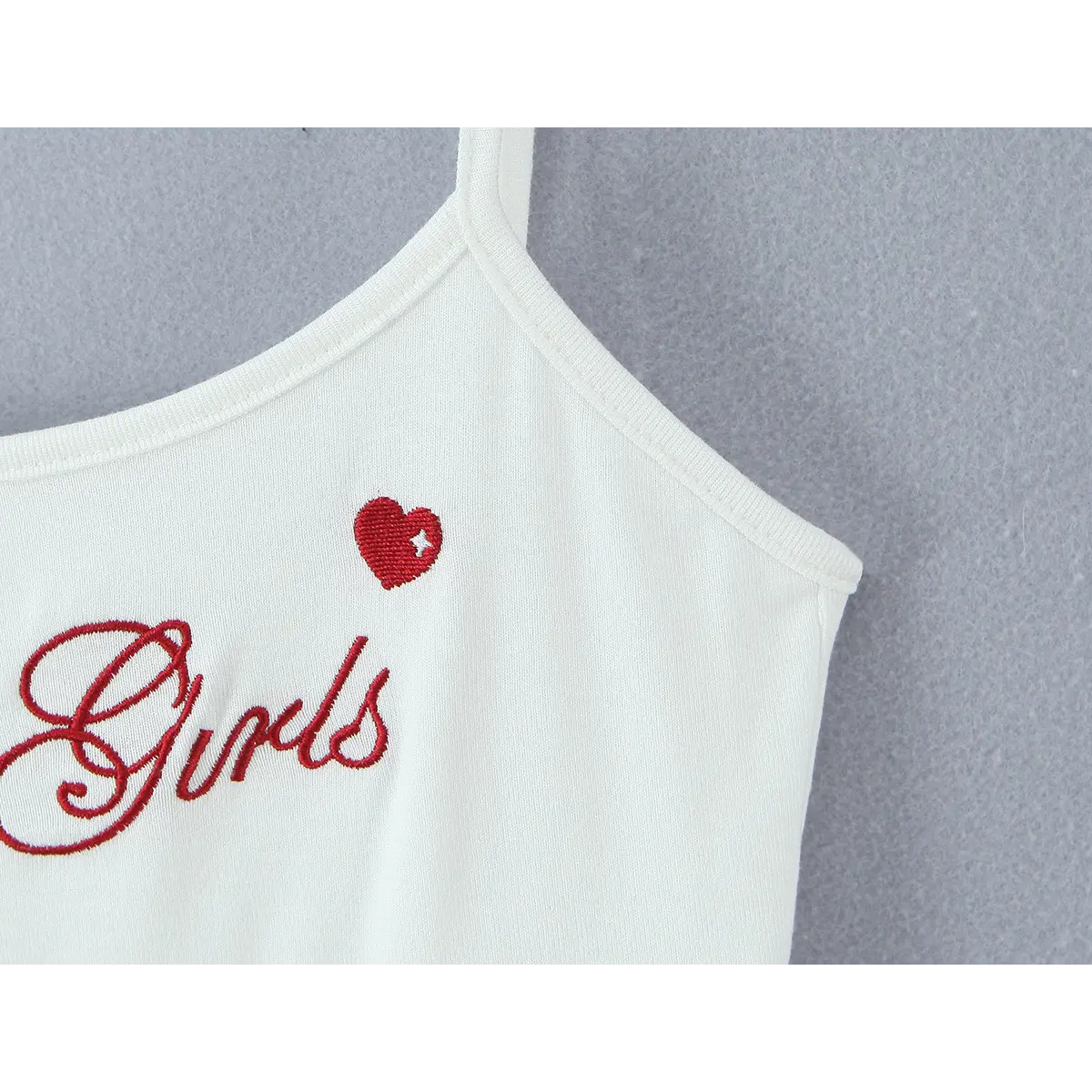 Close-up of the red embroidered text "Moná Girls" and a small red heart with a star detail.