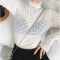 Model wearing white sheer mesh turtleneck long sleeve top with crescent moon pattern