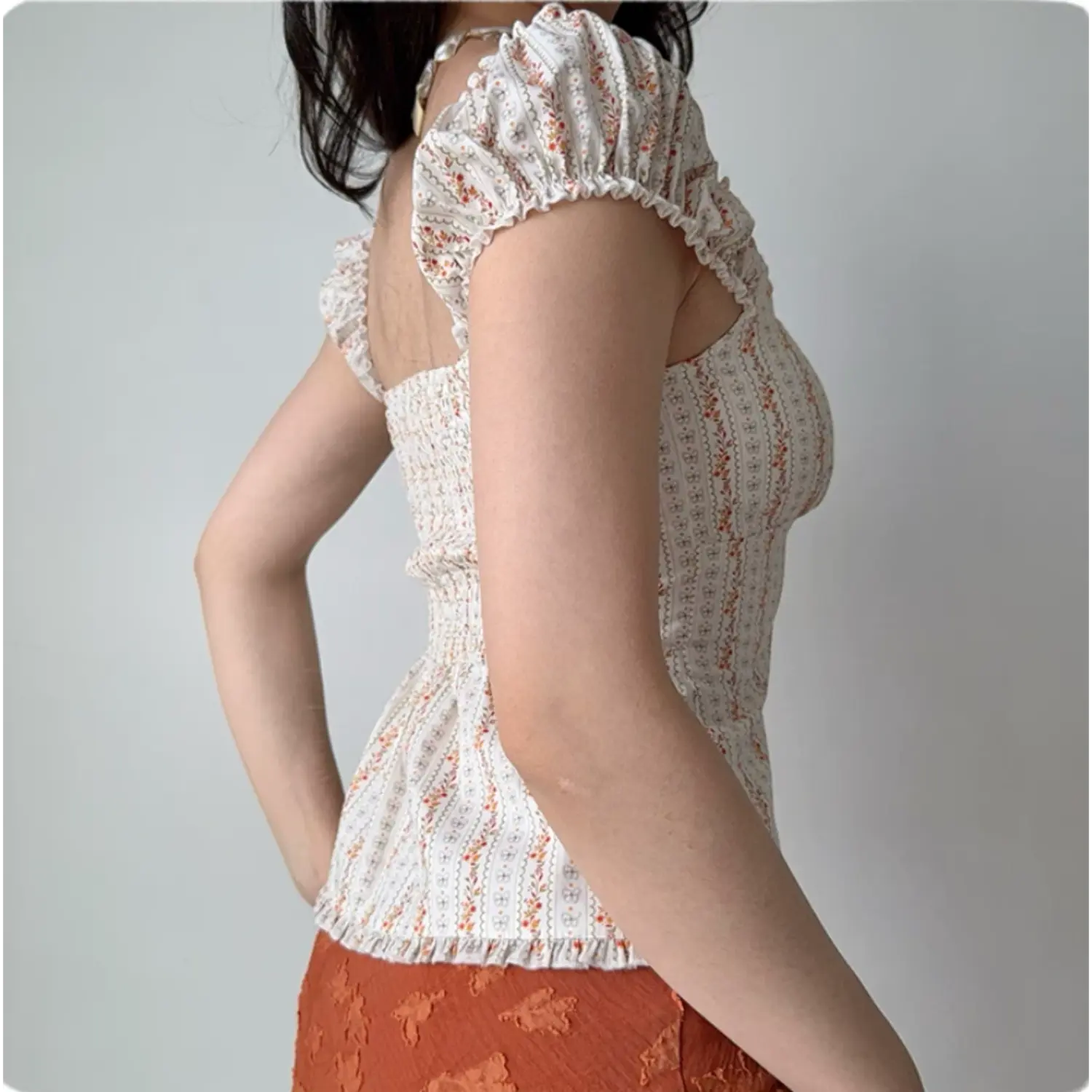 Back lifestyle shot on model of white floral stripe blouse, smocked waist, short puff cap sleeves, vintage fitted waist top