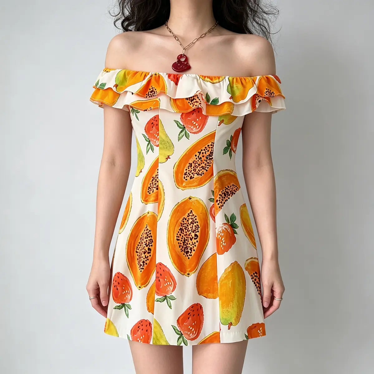 Model wearing an off-the-shoulder mini dress with a watercolor-style papaya and strawberry print, featuring a ruffled neckline.
