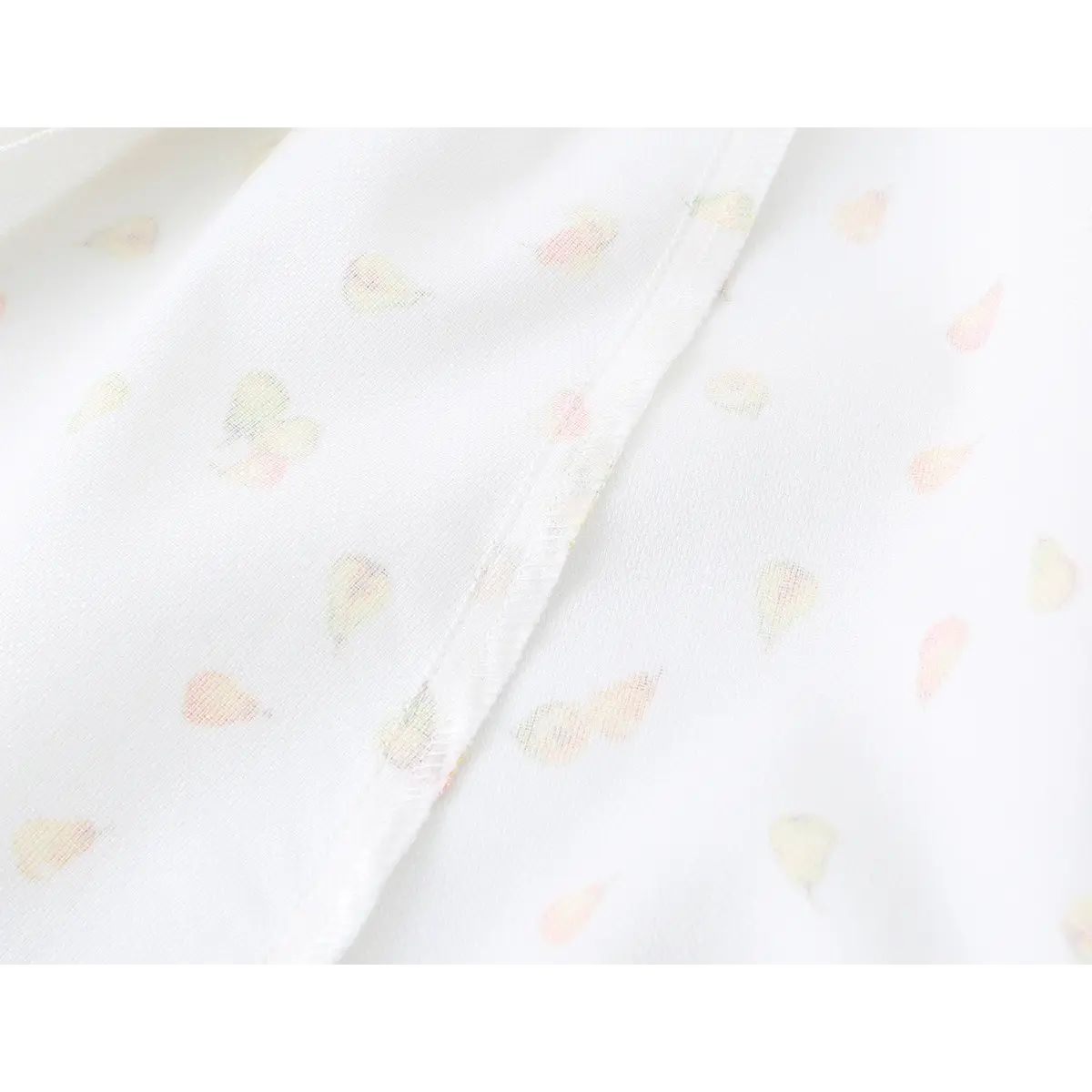 Close-up detail of the fabric texture and watercolor pear print on a white strapless mini dress.