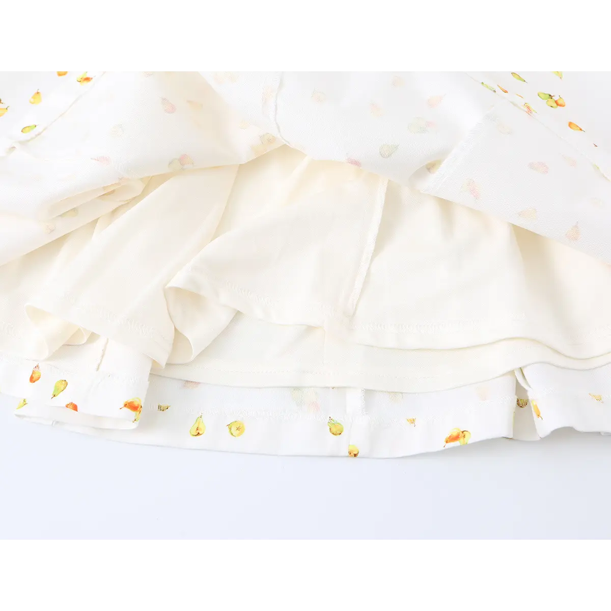 Close-up detail of the interior lining and hem construction of a white strapless mini dress with watercolor pear print.