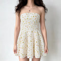 Model wearing a white strapless mini dress with watercolor pear print, featuring a structured bodice and flared skirt, front view.
