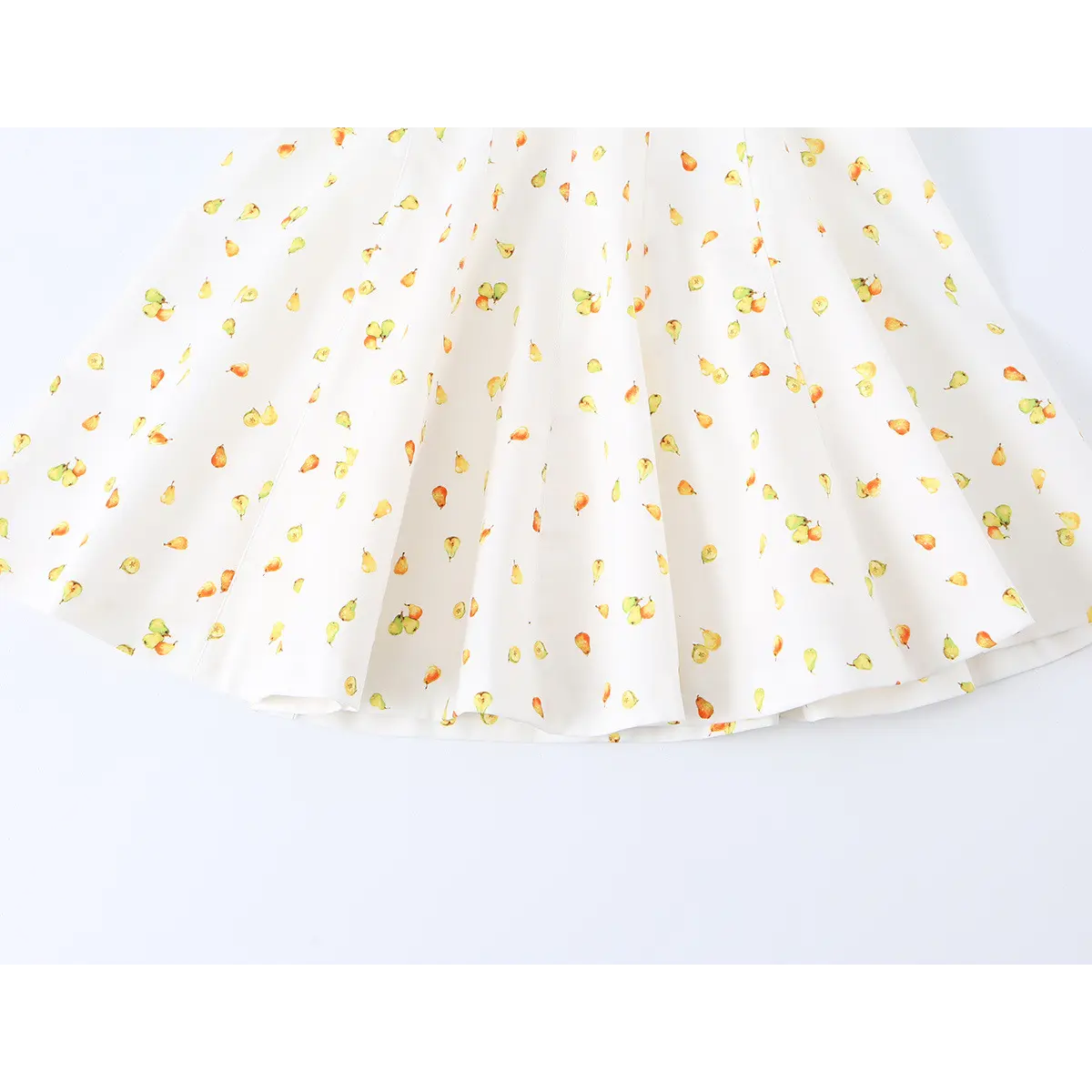 Close-up detail of the flared skirt and vertical seams on a white strapless mini dress with watercolor pear print.
