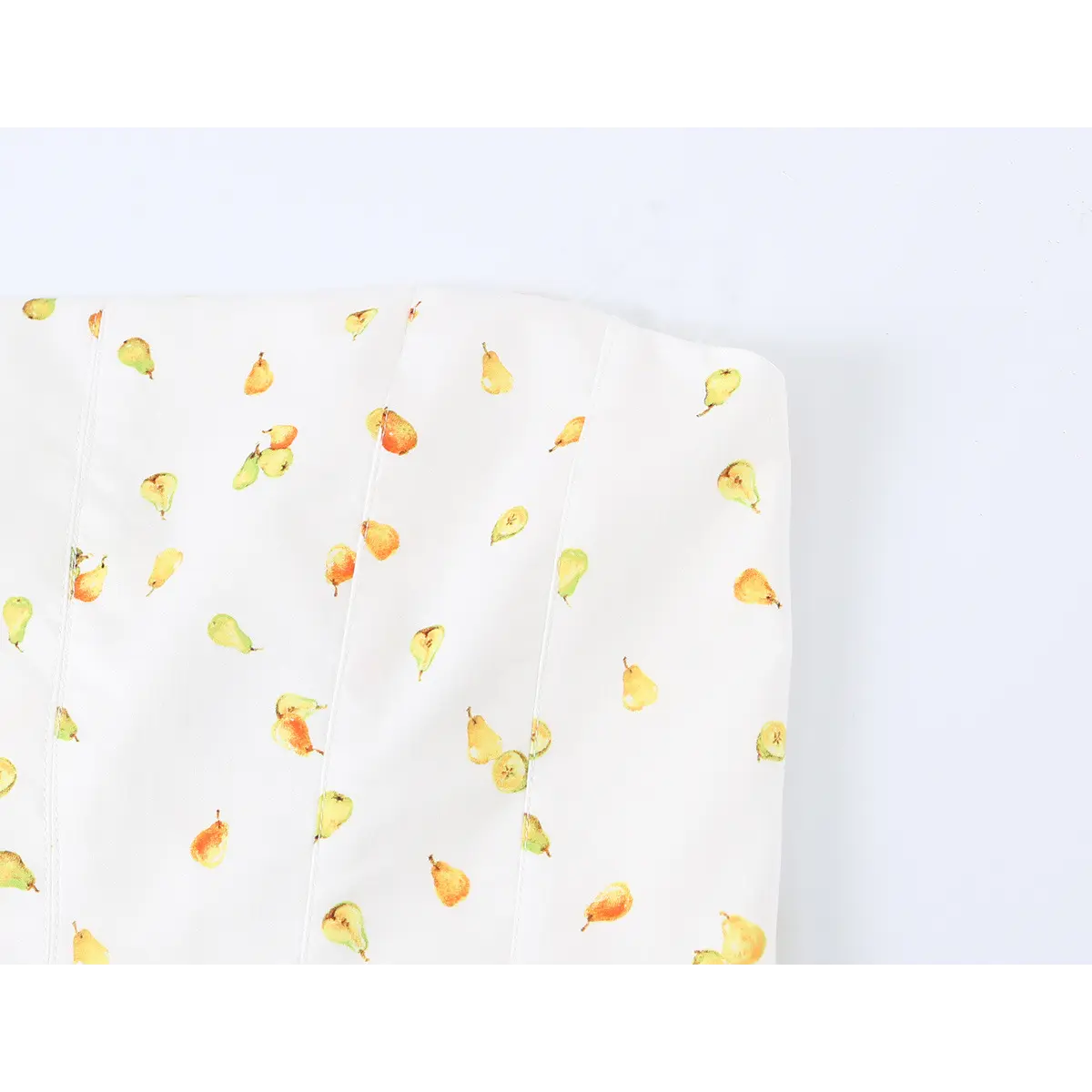 Close-up detail of the strapless top edge and vertical seams on a white mini dress with watercolor pear print.