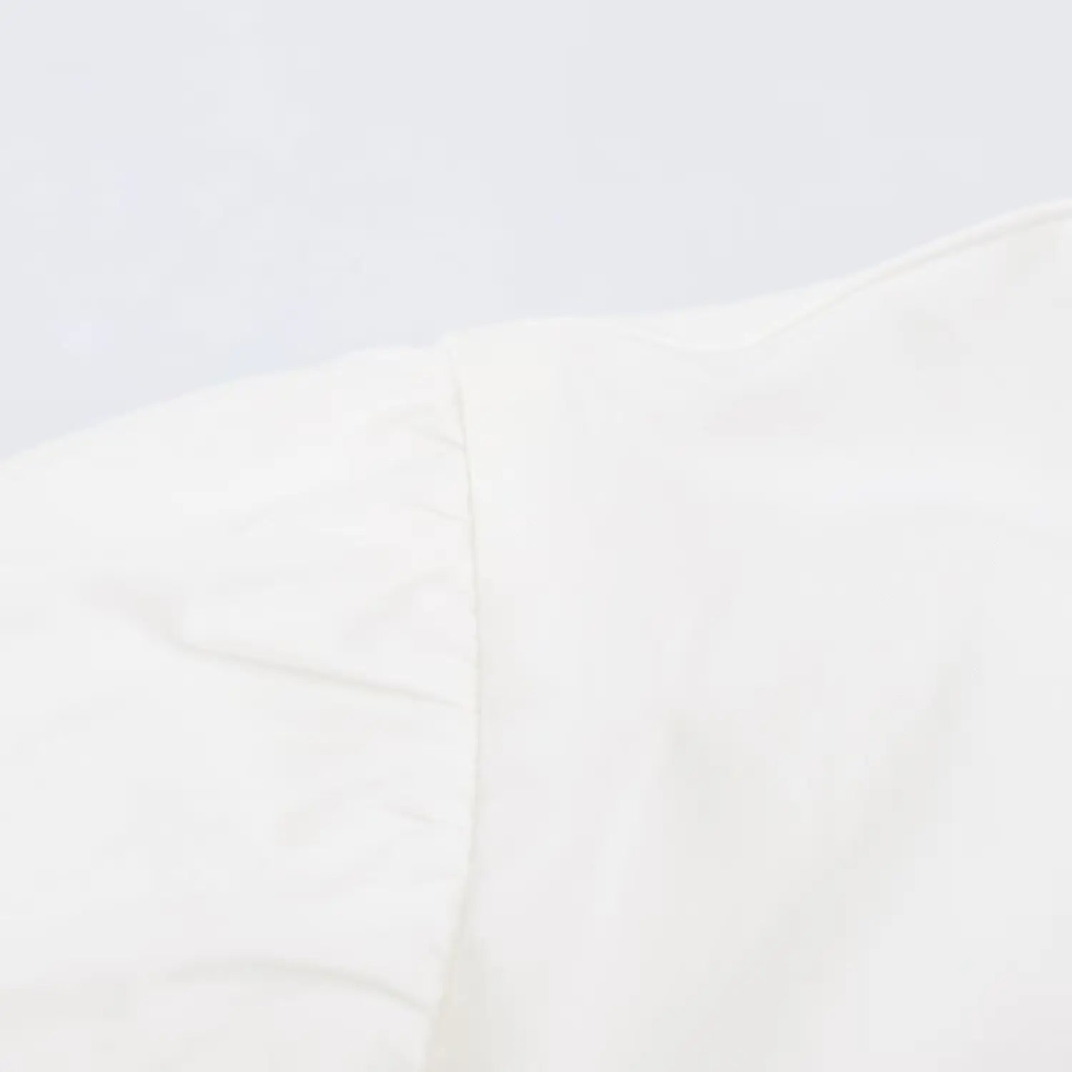 Close-up stitching detail of gathered cap sleeve on white peplum collared shirt