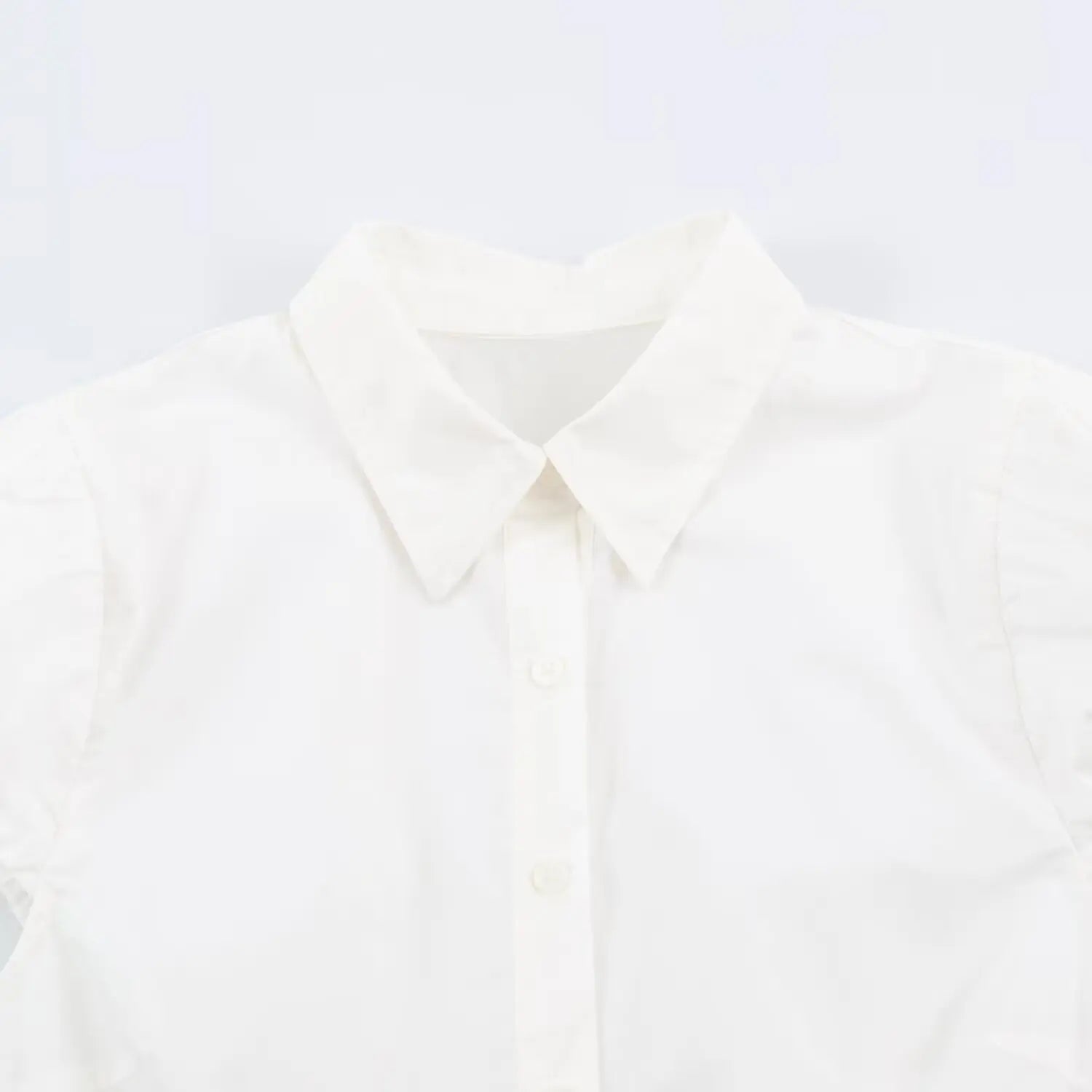 Close-up shot of pointed collar and front buttons on white peplum shirt