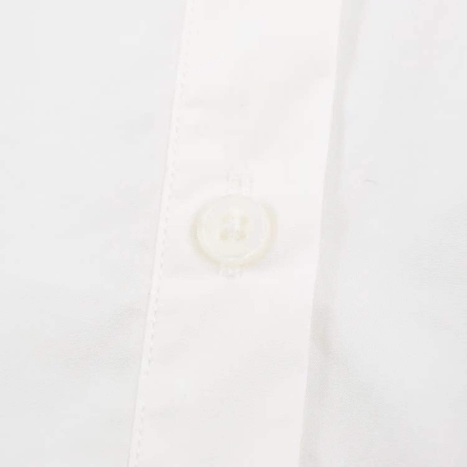 Close-up round front button and stitching placket on white peplum shirt