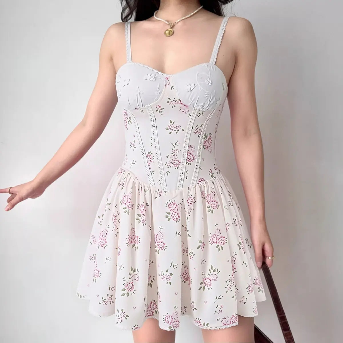 Woman wearing white bustier-style cami dress with pink floral print, full front view