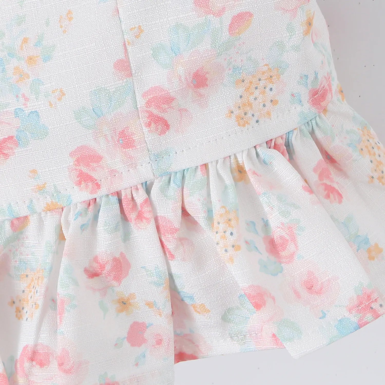 Women white pastel floral crop top hem close-up, ruffle spliced watercolor floral woven fabric flat lay detail