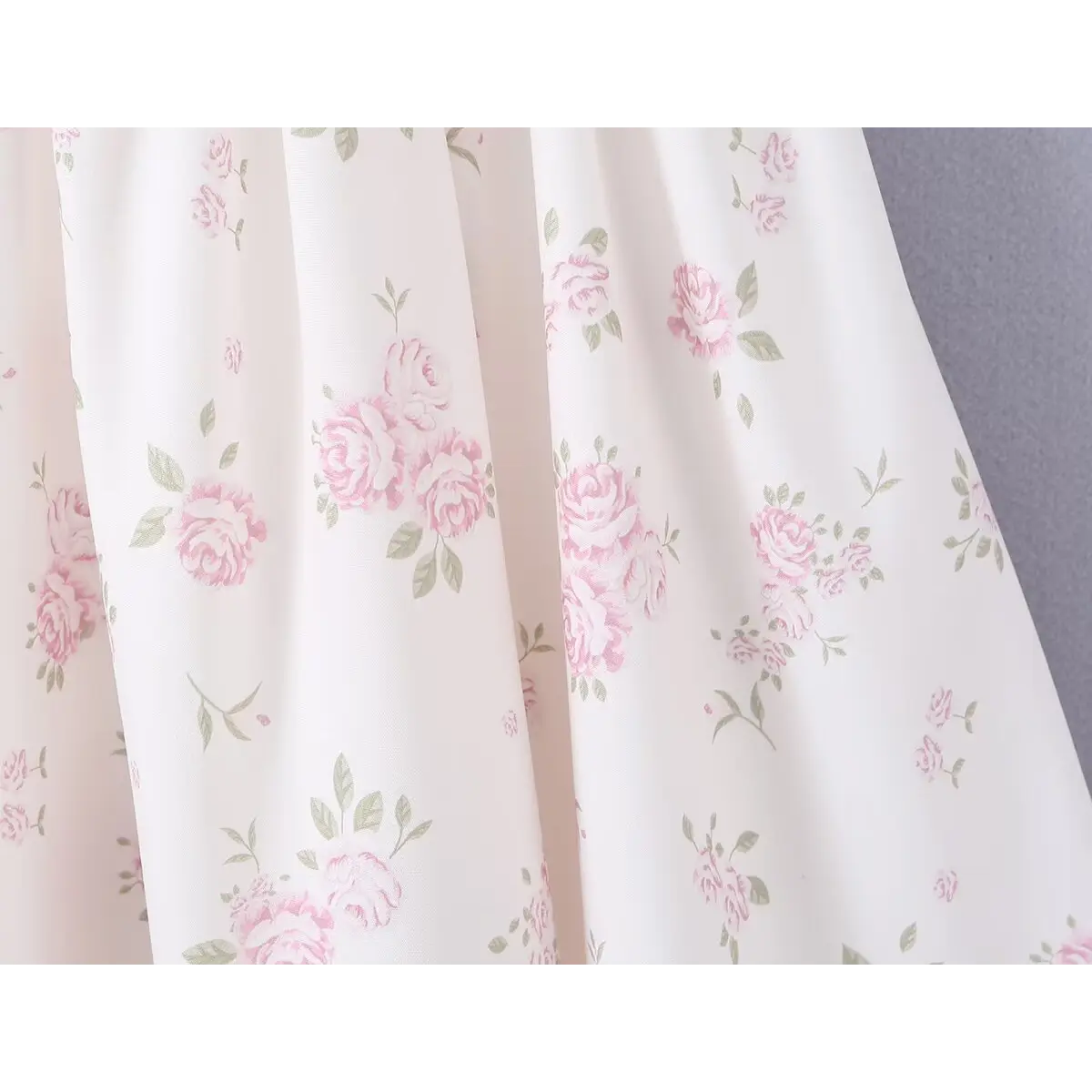 Close-up of the pink rose floral print and lightweight fabric texture on the white dress