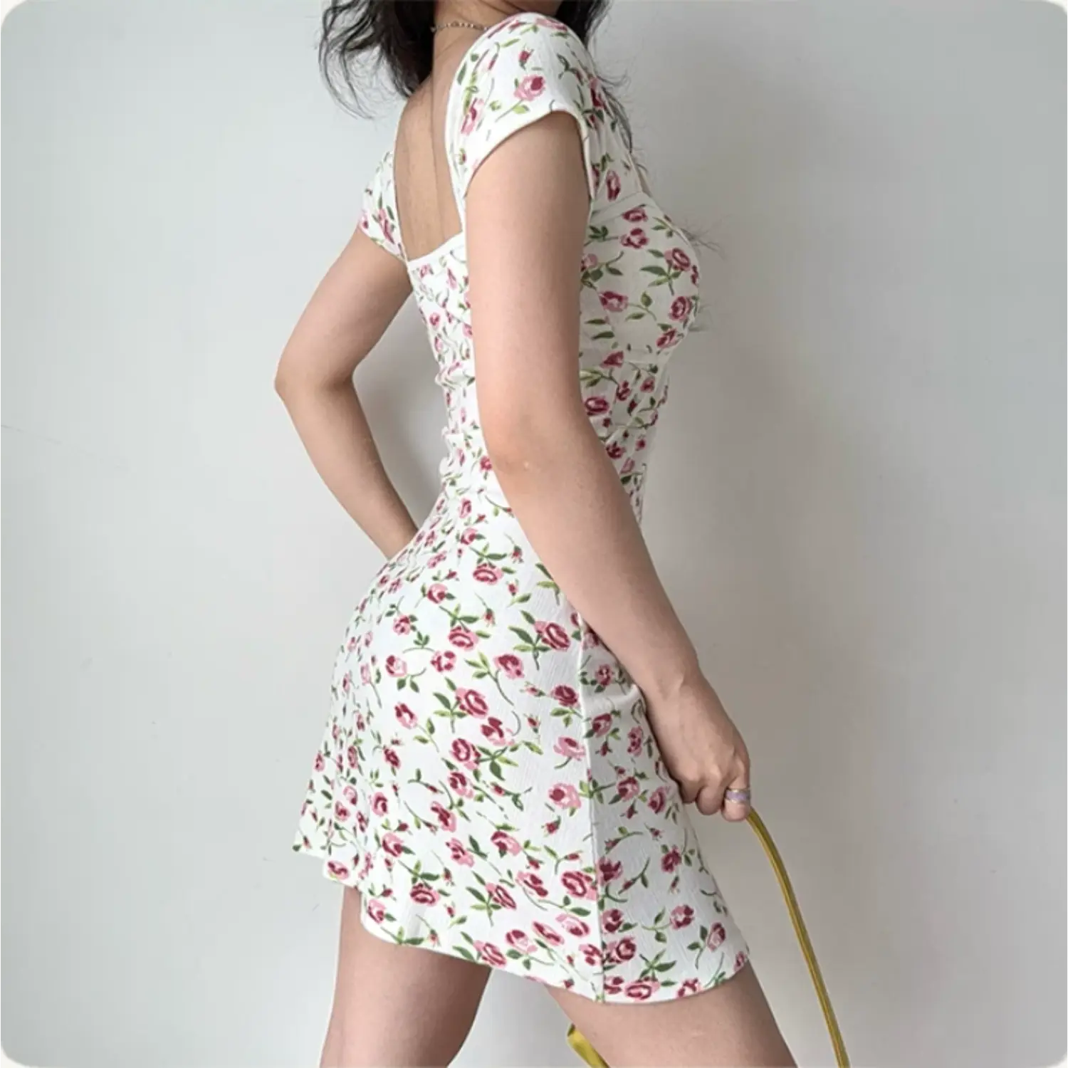 Back lifestyle shot on model of white pink rose floral ribbed mini dress, cap short sleeves, fitted bodycon casual short dress